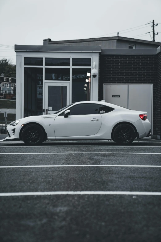 a white car in a parking lot next to an empty building