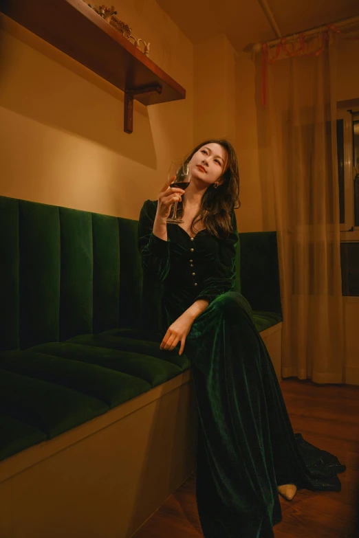 woman sitting on a green velvet bench and talking on a phone