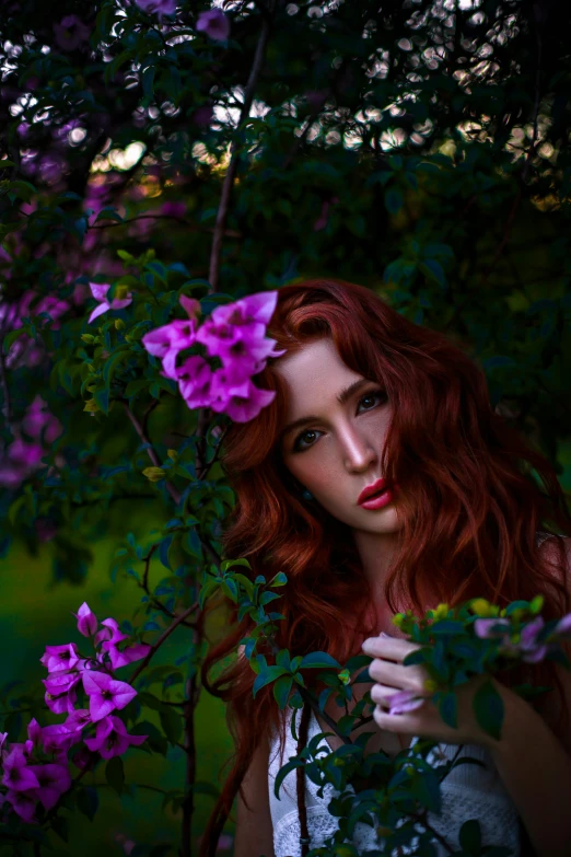 a beautiful young woman posing in front of purple flowers