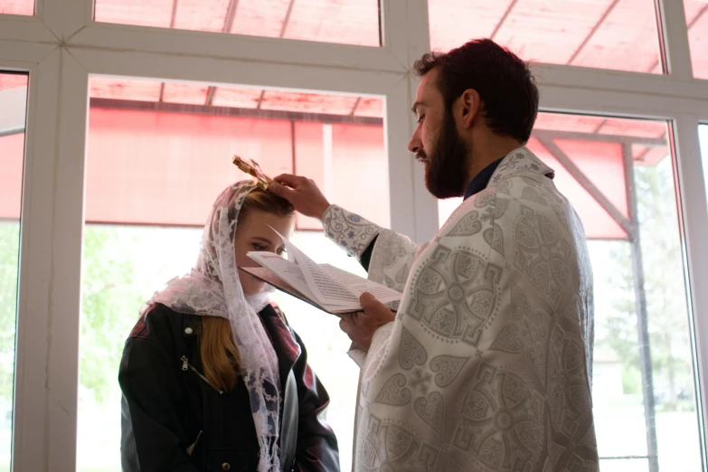 a woman is wearing a veil while a man gets a piece of fabric