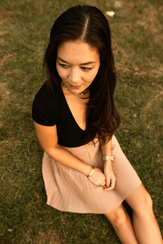 an asian woman is sitting in the grass