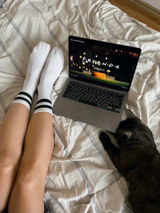 a girl's legs laying down next to a laptop