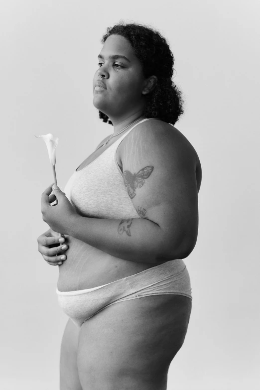 a large woman holding a flower while wearing underwear