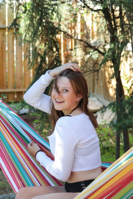 a young woman smiling while sitting in a colorful hammock