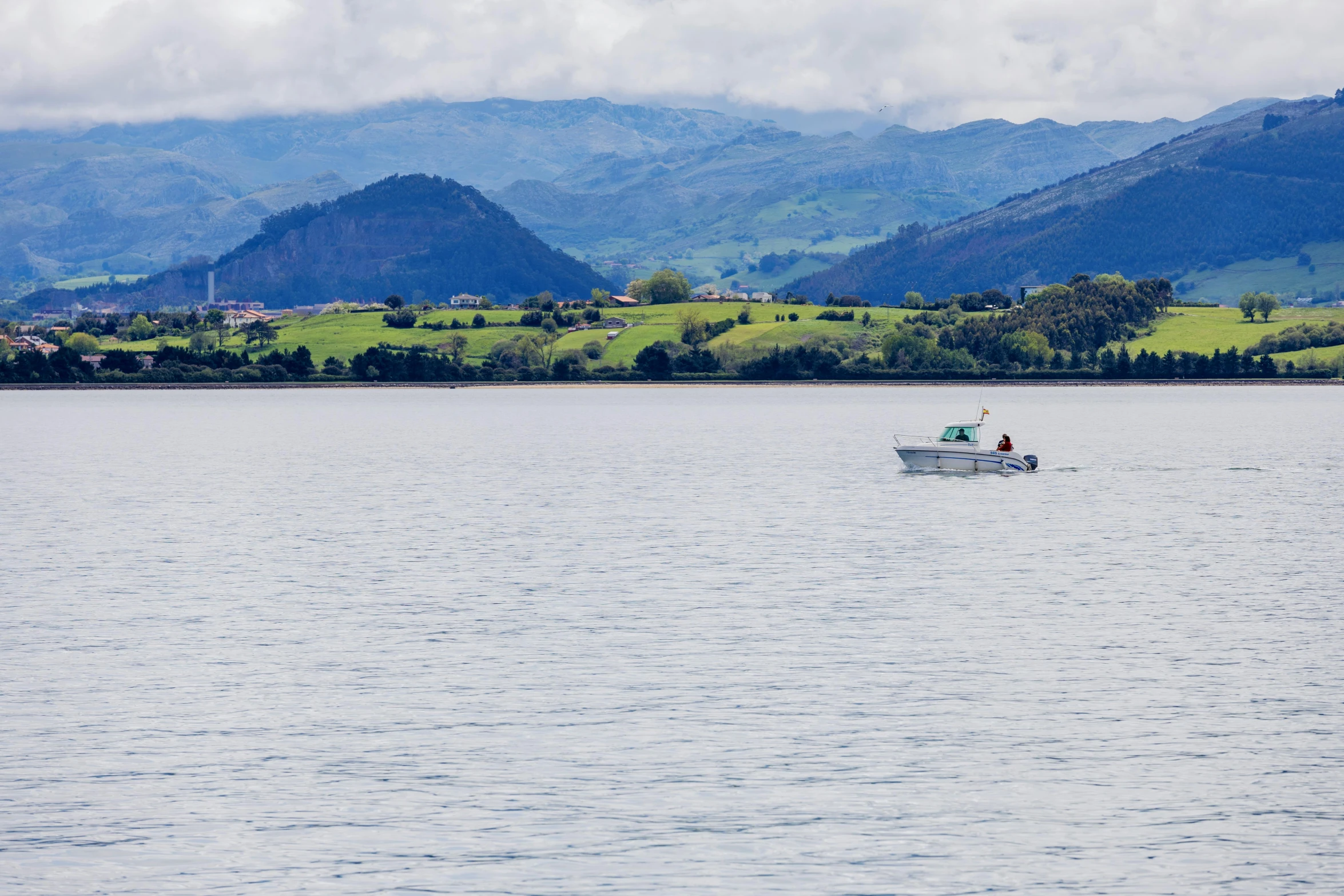 people in a small white boat traveling across a large lake