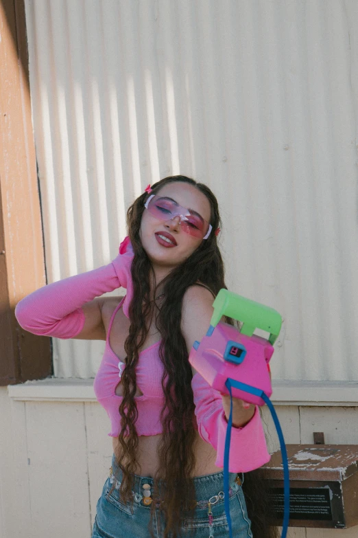a girl with a pink shirt and sunglasses, holding a pair of blue scissors