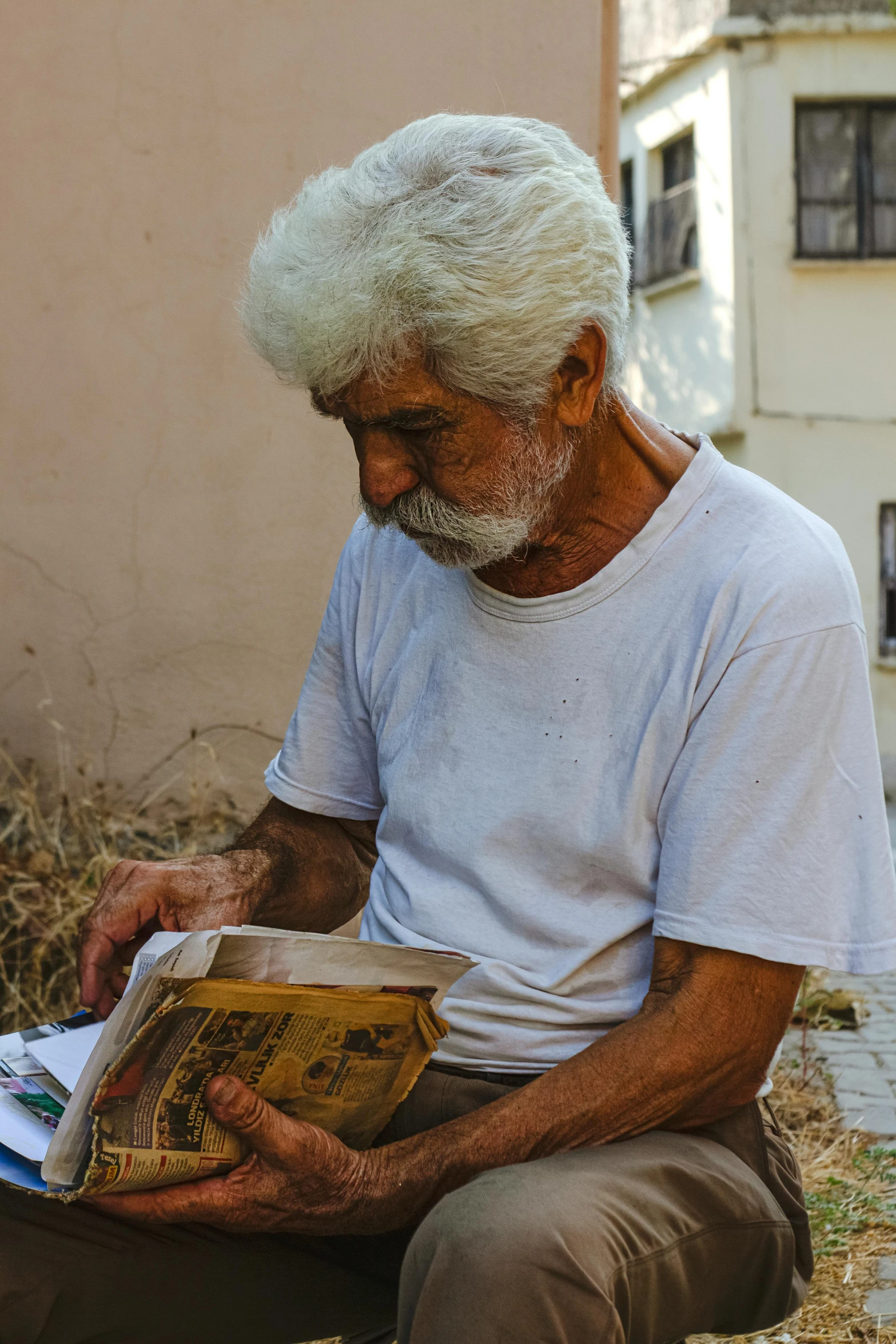 a old man is sitting outside reading