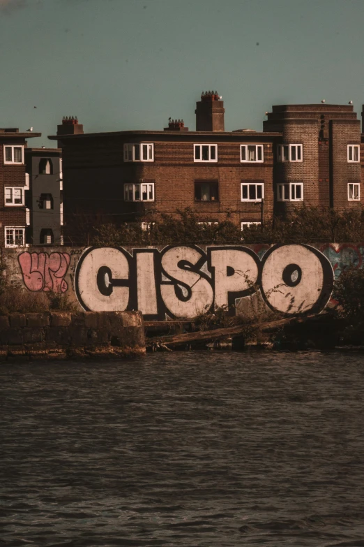 a wall with graffiti writing on it near the water