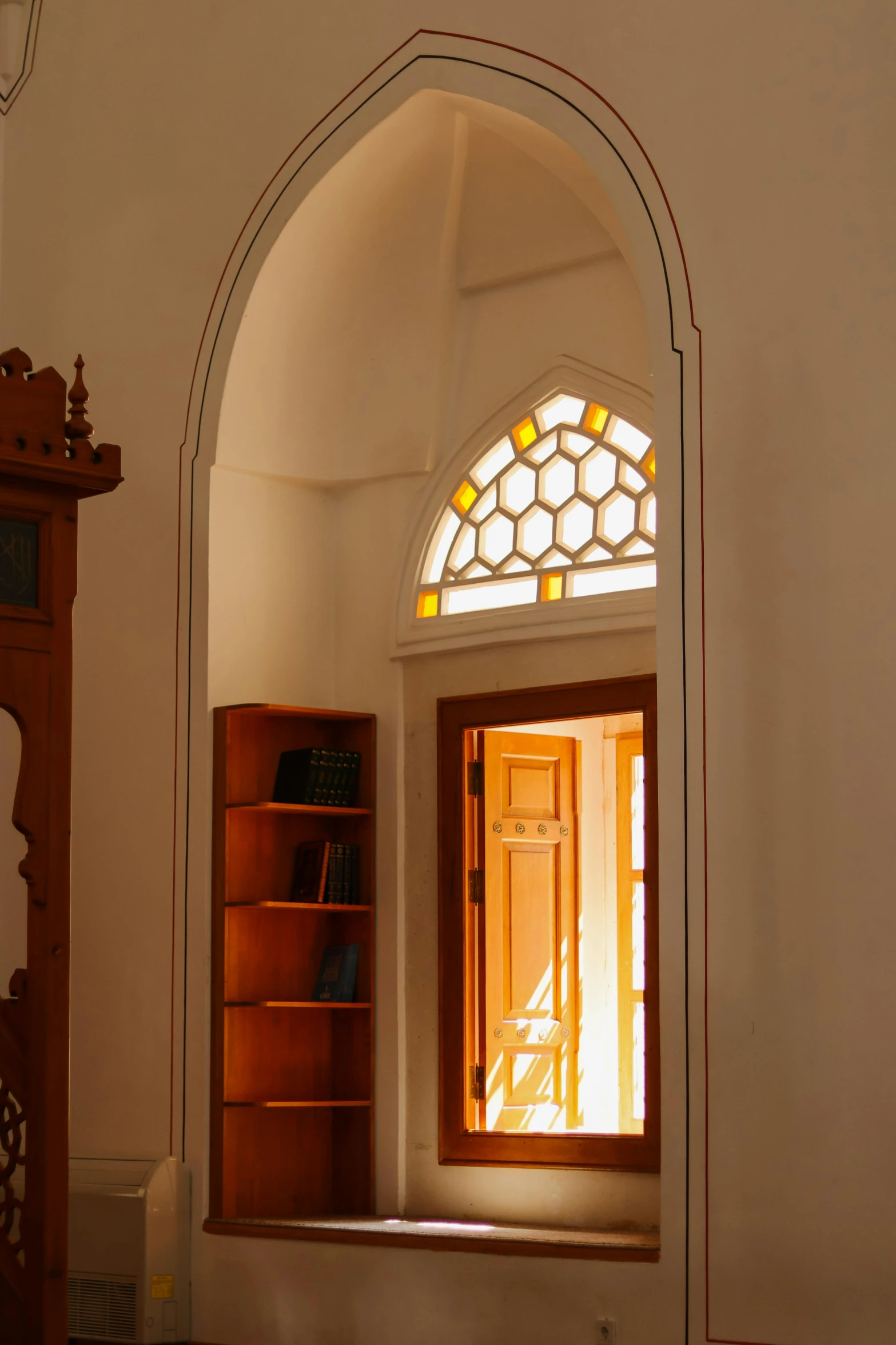 a window with arched wooden frame sitting next to a book shelf