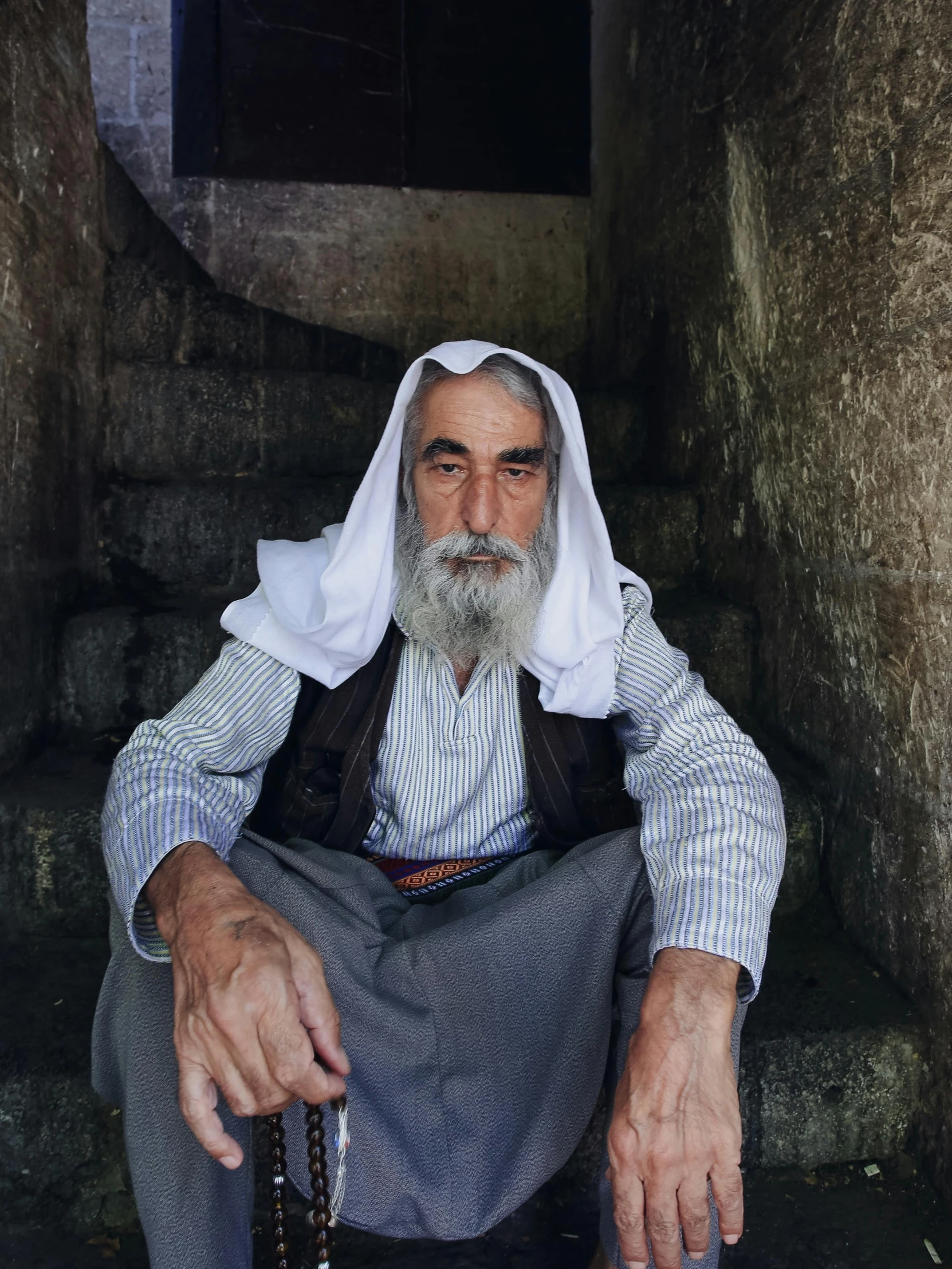 a man with grey beard and white hair sitting on stairs