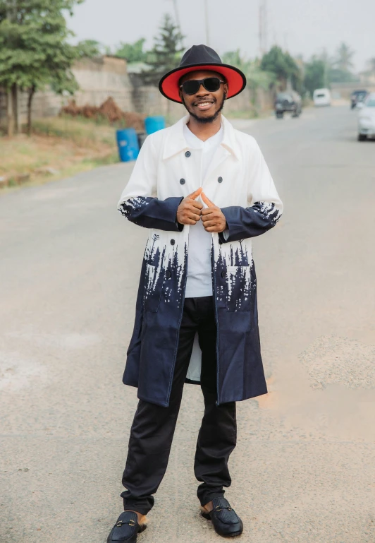 man in an african - style outfit with hat standing on the street