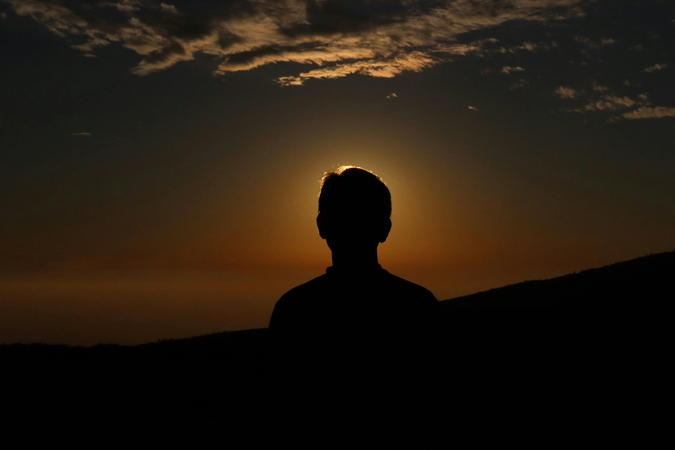 silhouetted pograph of a man at sunset on a hill
