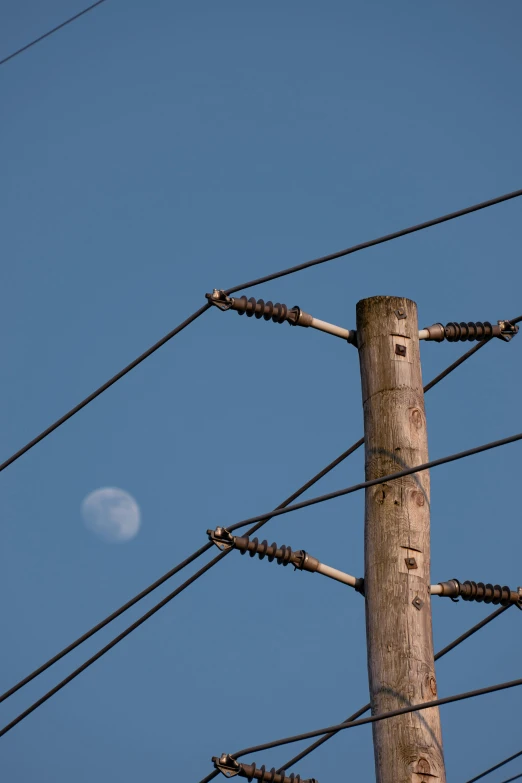 a po of a wooden pole with power lines and telephone wires