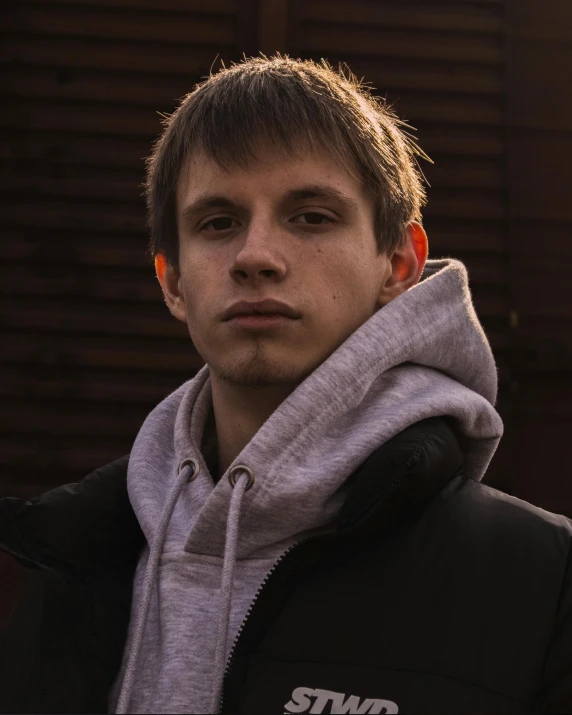 a young man in black and white hoodie next to a building