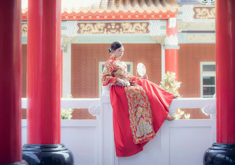 a woman in chinese clothing sitting on a ledge