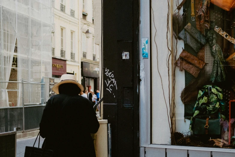 a man wearing a hat walks through the city