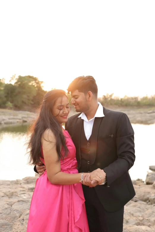 a newly married couple holding hands on a rocky beach