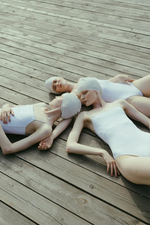 three mannequins laying on the ground on a wood deck