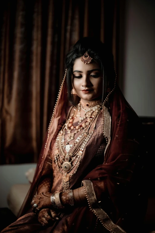 a woman in an elegant outfit with jewels sits on the floor