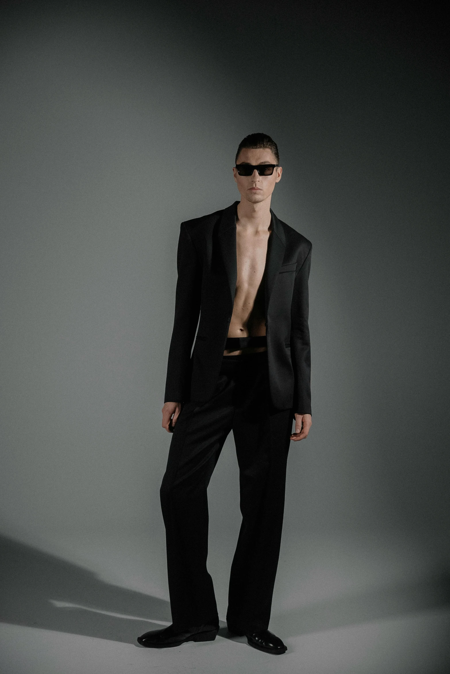 an shirtless man in a tuxedo poses for a studio po