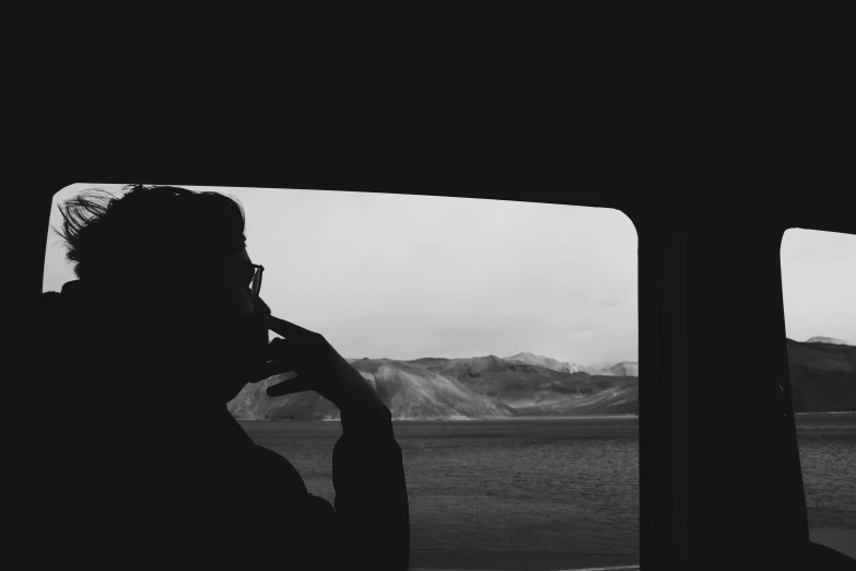 a man looks out of a window while talking on a cell phone