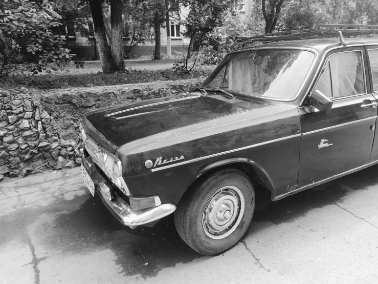 the old car is parked next to a wall