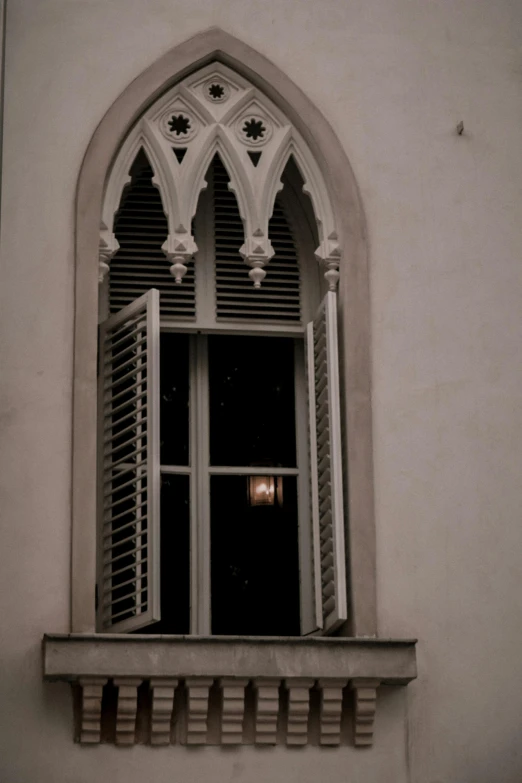 a window with a closed shutter and ornate arch