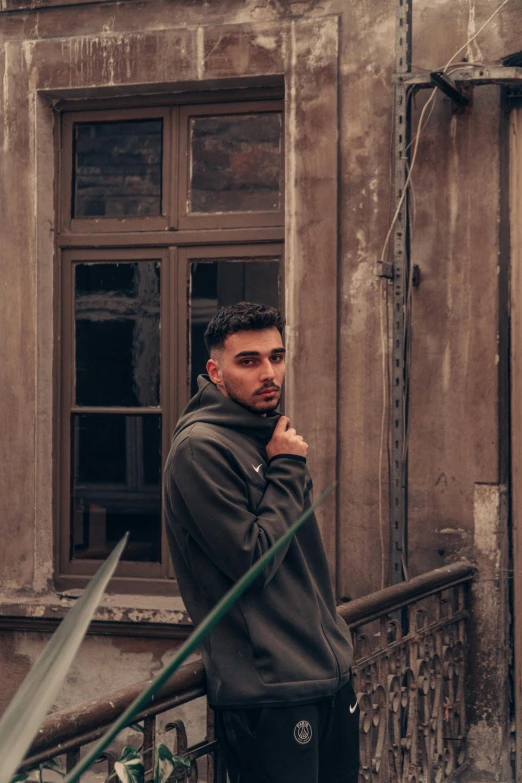 a man posing for a picture with his arms folded next to a window