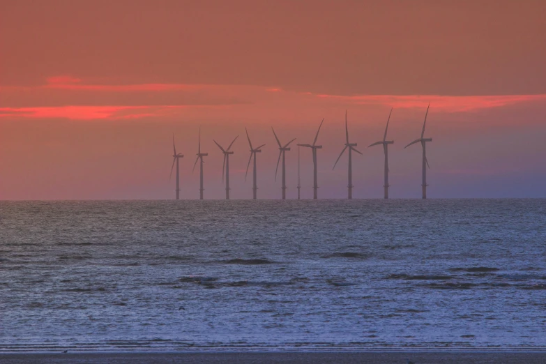 a group of wind turbines that are in the ocean