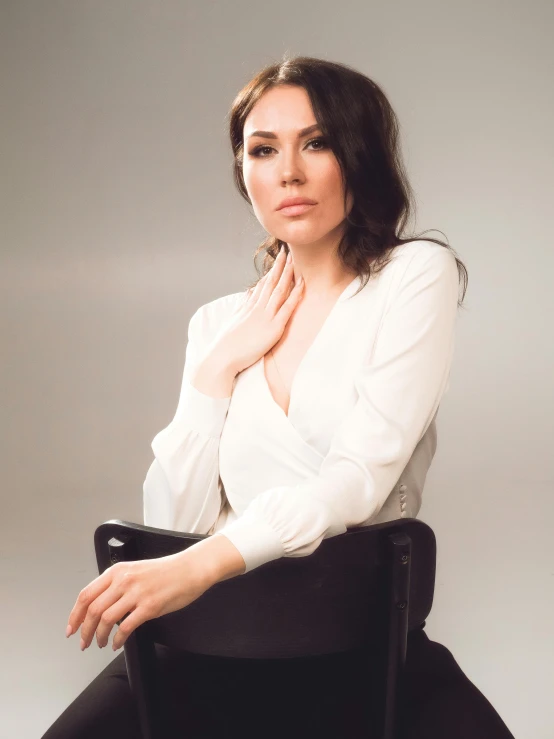 a woman sitting in a black chair with her hand on the chin