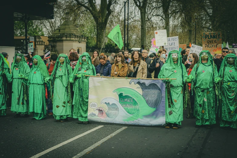 there are many people in green outfits holding signs