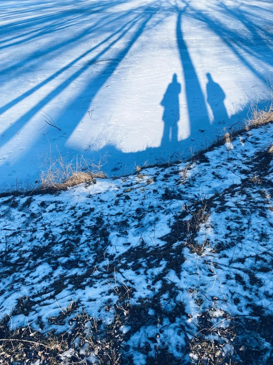 two people shadowed on snow covered ground