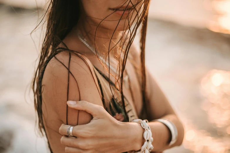 a woman in a white dress looking down at her wrist and celet