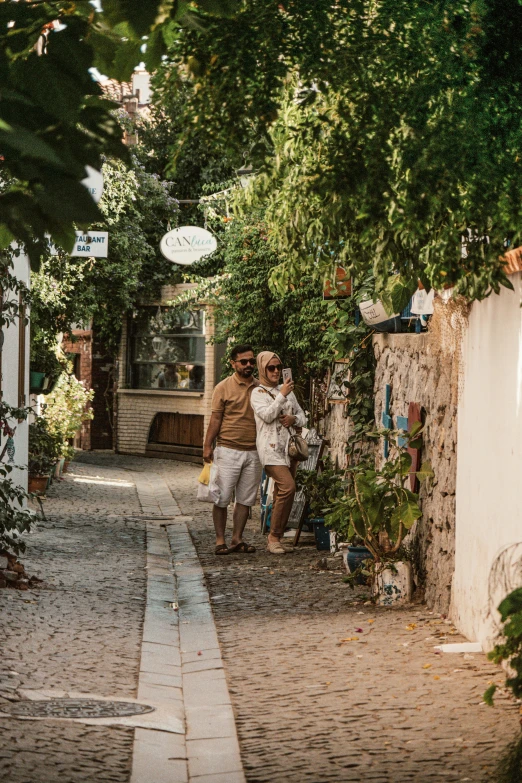 two people are walking down a path under the trees