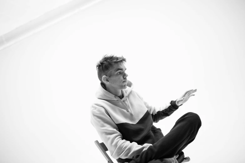 man sitting on chair with arms spread out, facing left