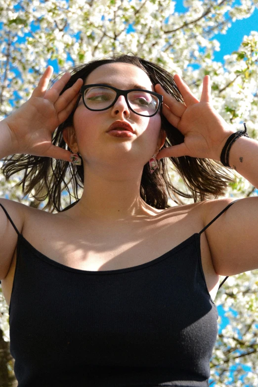 a woman with glasses and a black tank top looking up
