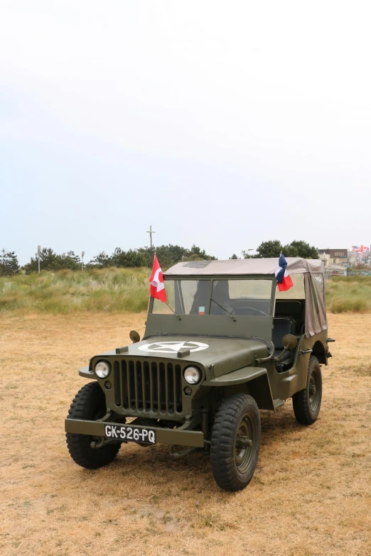an old fashioned military jeep is parked on the grass