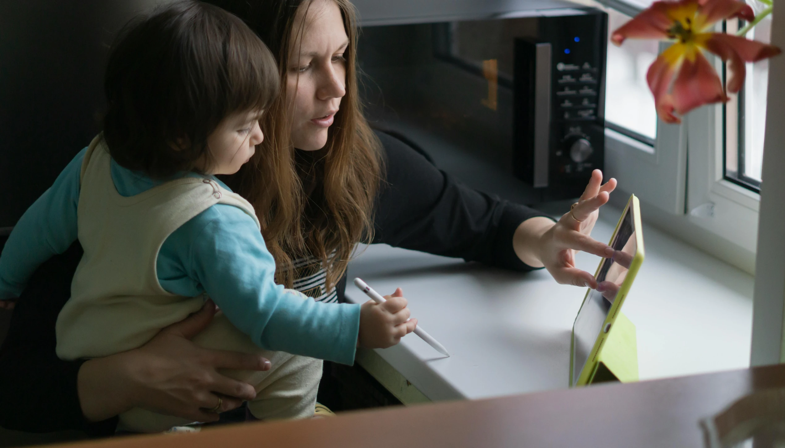 the woman is teaching the small child how to use the laptop