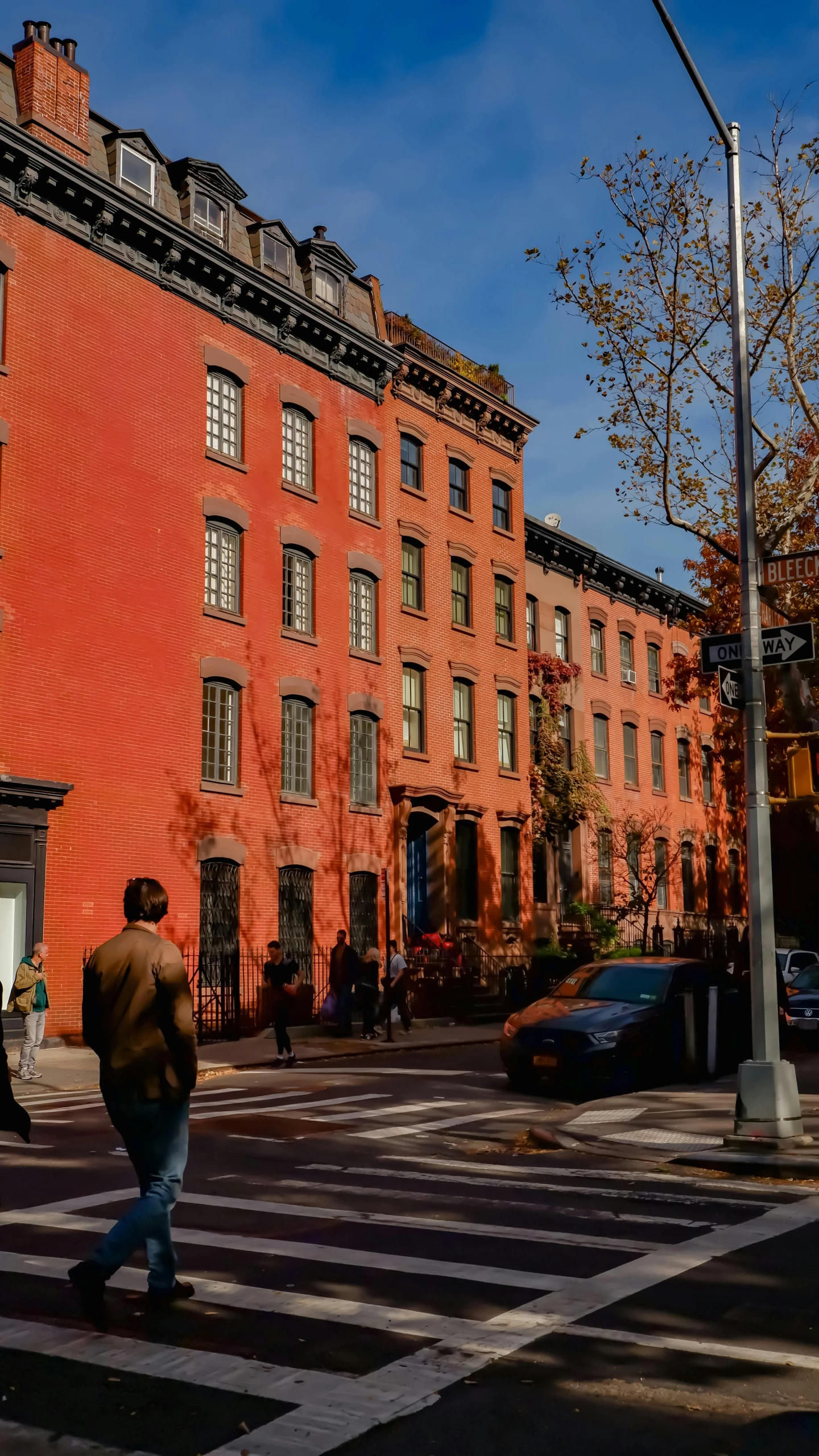 a man walking across a cross walk in front of brick buildings