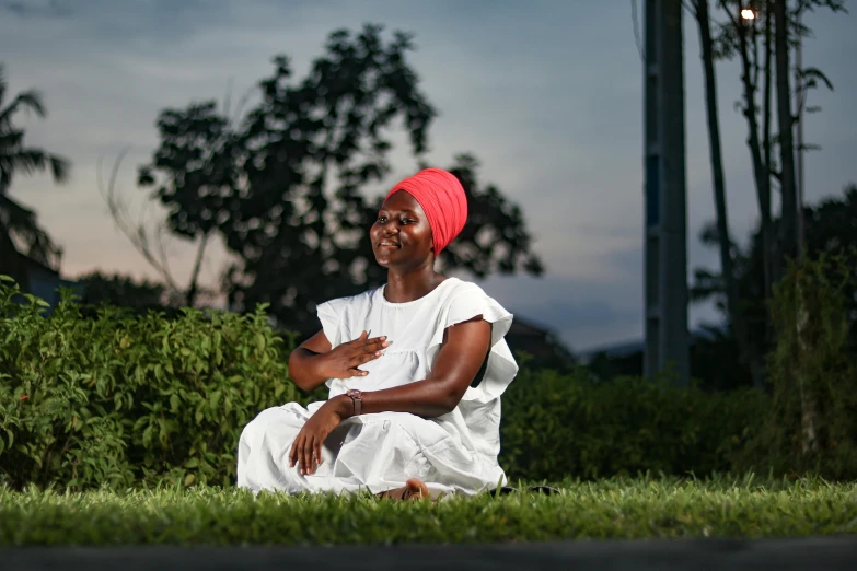 a woman is sitting in the grass looking at the camera