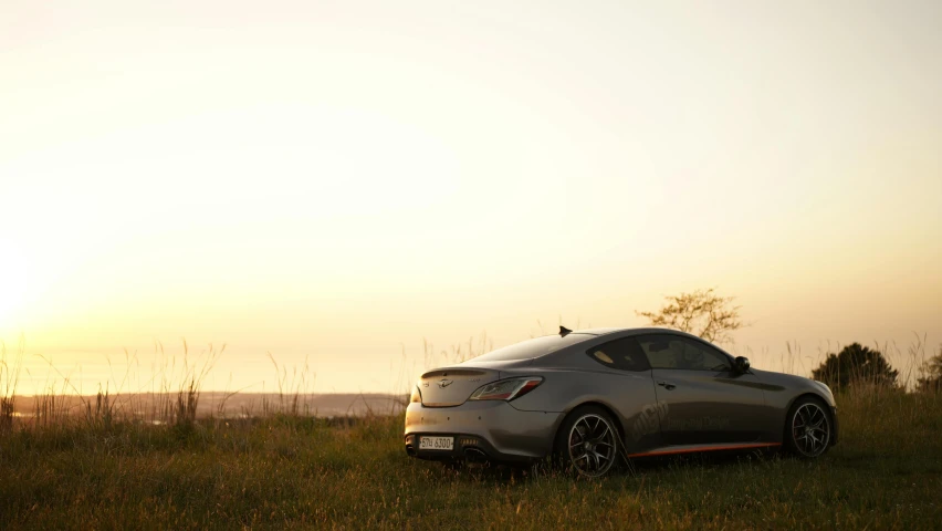 a gray car parked on the grass in the afternoon