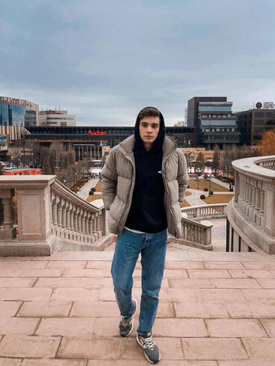 a young man with his hands in his pockets standing on a bridge