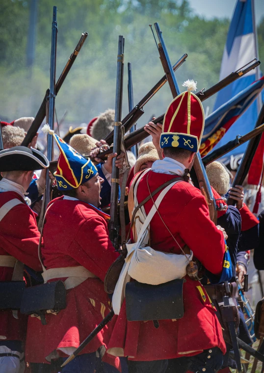 a group of men dressed in red uniforms are holding rifles