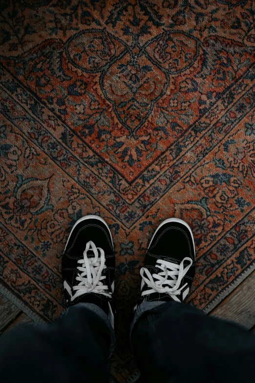 the feet of someone standing on the floor near a rug