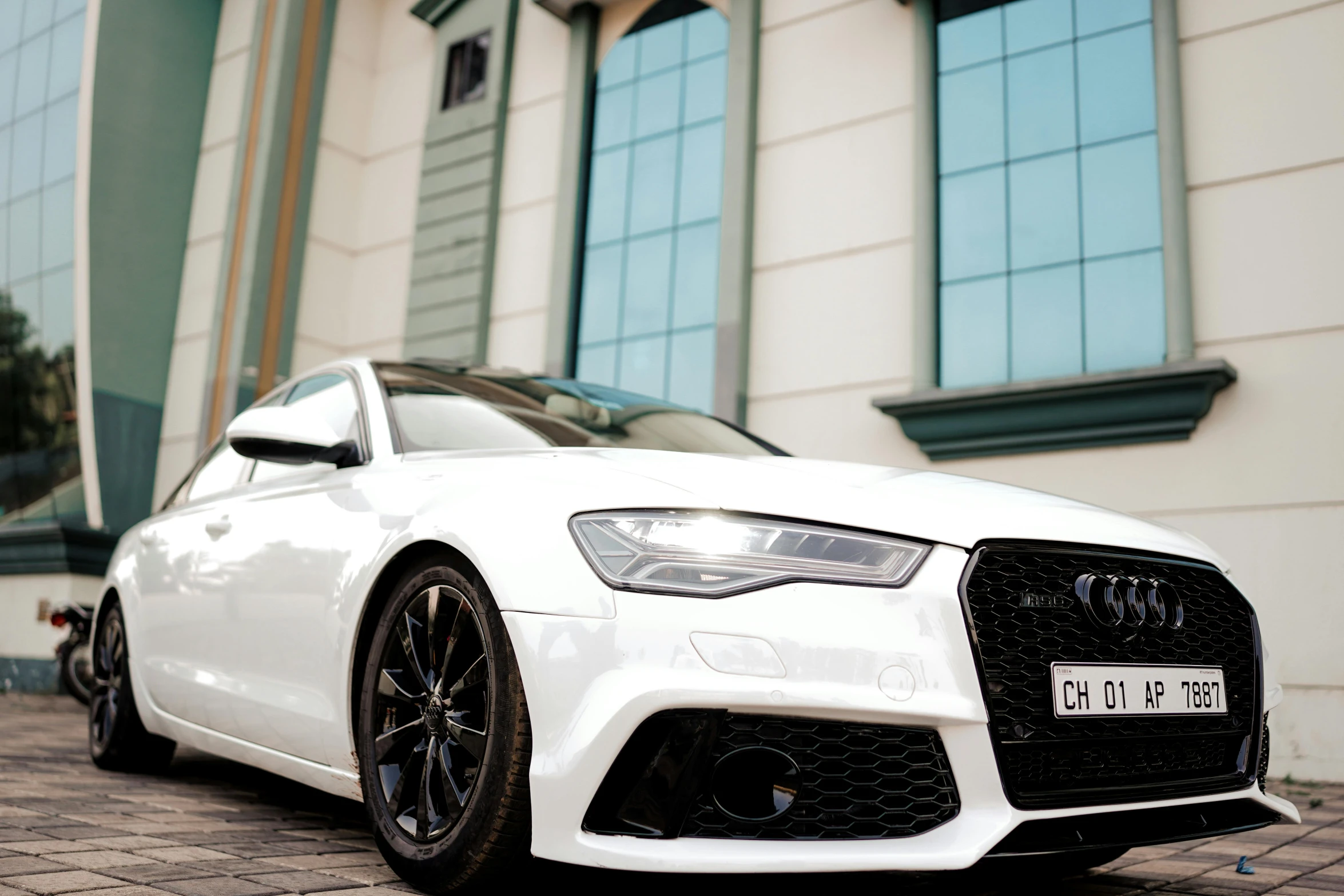 a white audi car with red front kes parked in front of a building