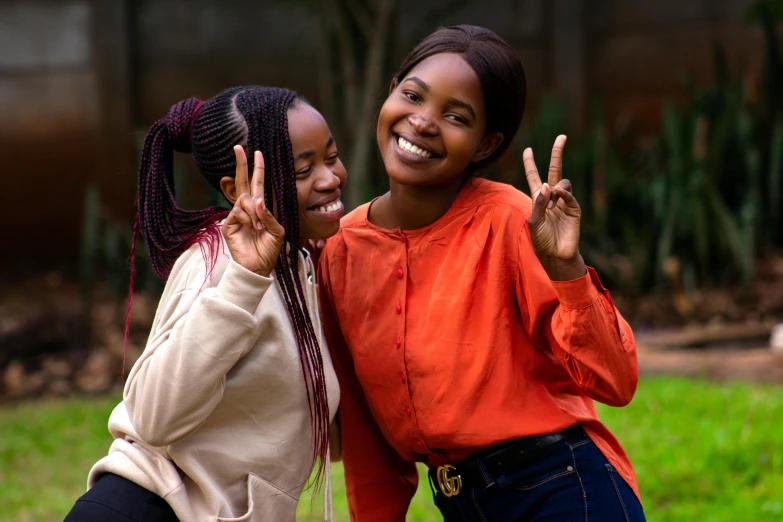 two young women giving a peace sign in a park