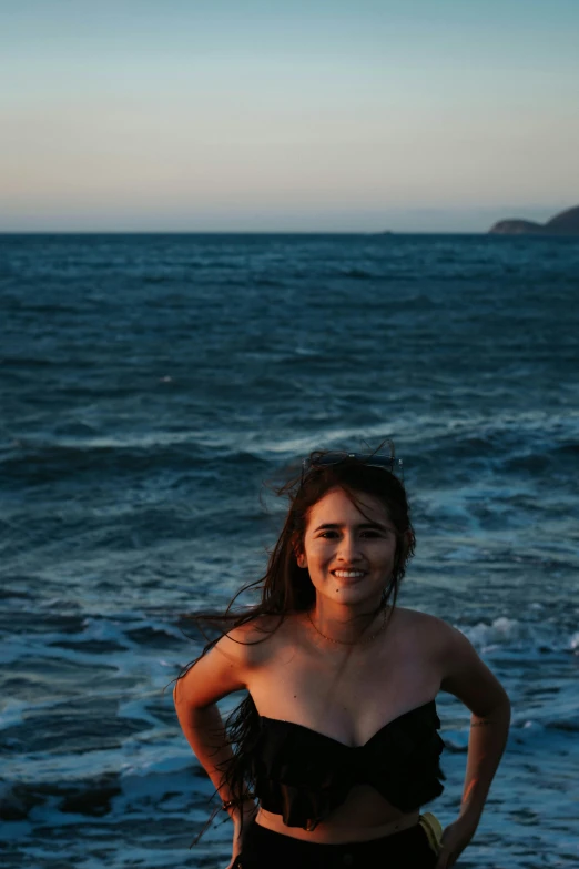 a young woman posing on a rocky beach next to the ocean