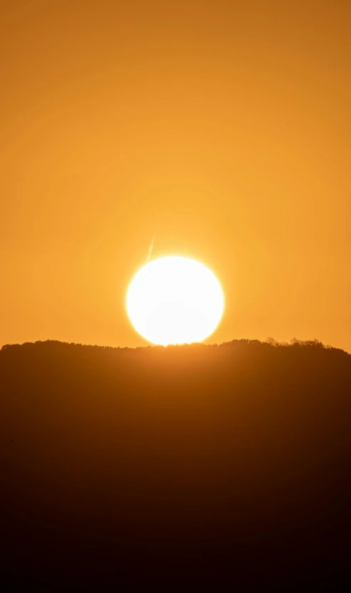 the sun is setting behind some hills