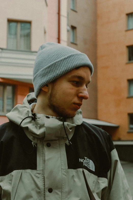 a young man is wearing a hat and standing in front of some buildings