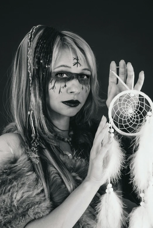 a woman in costume holding up a dream catcher